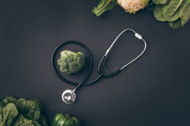 top view of stethoscope with broccoli and cauliflower on gray table  clipart