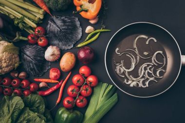 top view of colored vegetables and frying pan on gray table clipart