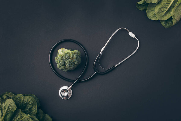 top view of stethoscope with broccoli on gray table 