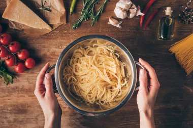 Spagetti makarna ve malzemeler ile el ahşap masa üzerinde yukarıdan