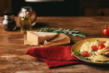 geleneksel İtalyan pasta plaka Parmesan, biberiye ve yağ ile ahşap tabloda roka ve domates ile
