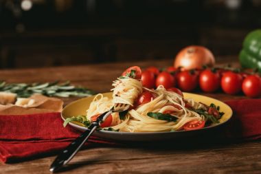 traditional italian pasta with tomatoes and arugula in plate with fork clipart