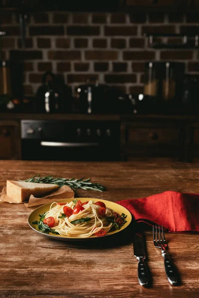 トマトとパルメザン チーズとローズマリーのテーブルの上皿にルッコラのパスタ — ストック写真