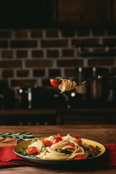 traditional italian pasta with tomatoes and arugula on fork