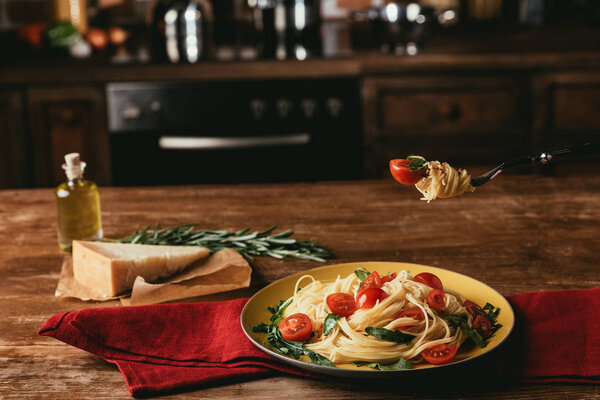 delicious italian pasta with tomatoes and arugula in plate on table with Parmesan and rosemary
