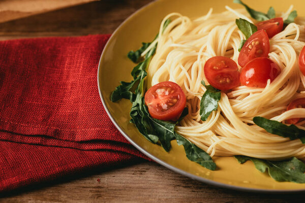 close up of traditional italian pasta with tomatoes and arugula in plate