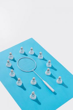 high angle view of badminton racket and shuttlecocks on blue paper, isolated on white clipart