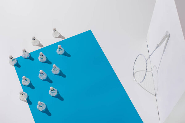 высокий угол обзора бадминтонной ракетки и шаттлов на голубой бумаге
