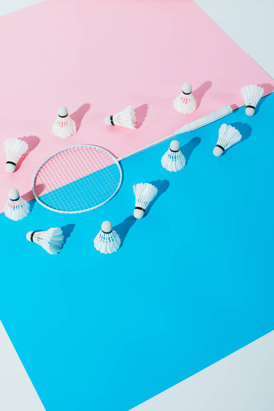 shuttlecocks around badminton racket on blue and pink papers