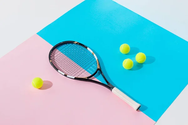 Tennis racket and yellow balls on blue and pink papers