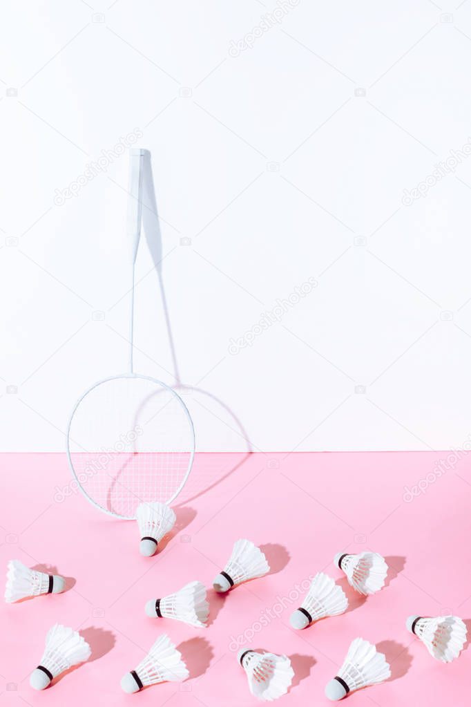 white badminton racket and shuttlecocks on pink paper at wall