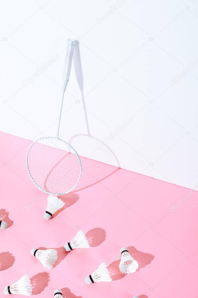 badminton racket and shuttlecocks on pink paper at wall