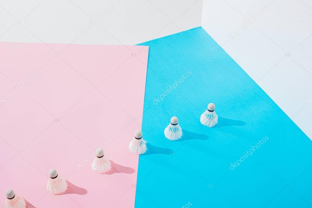 row of badminton shuttlecocks on pink and blue papers