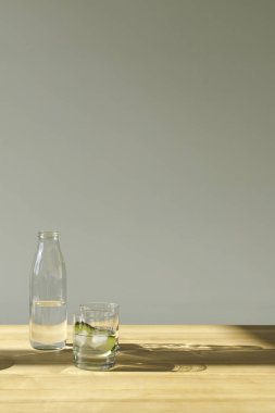 Maden suyu ve su ve salatalığın üzerinde ahşap masa ile cam şişe