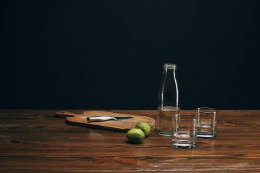 ahşap tahta bıçak, limes ve kahverengi masa üstü su ile