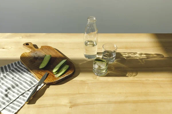Bovenaanzicht Van Gesneden Komkommers Fles Met Water Houten Tafel — Gratis stockfoto