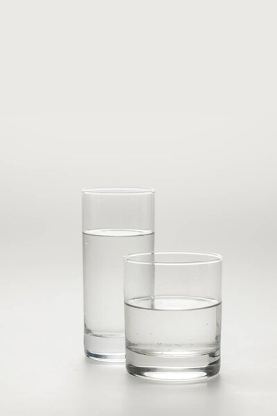 два различных стакана с спокойной водой изолированы на белом
 