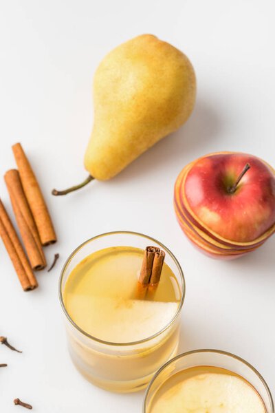 close-up shot of delicious spiced cider with apple and pear on white surface