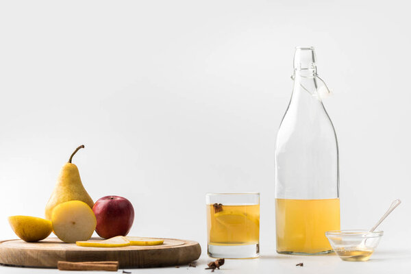 bottle of cider with apple and pear on wooden board on white