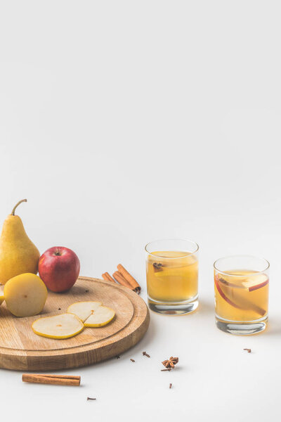 glasses of cider with apple and pear on wooden board on white