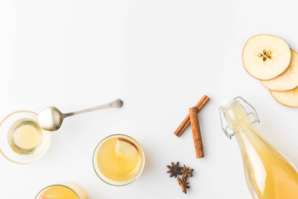 top view of apple cider composition with cinnamon sticks and glasses isolated on white
