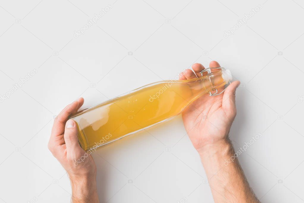 cropped shot of person holding bottle of apple cider on white surface