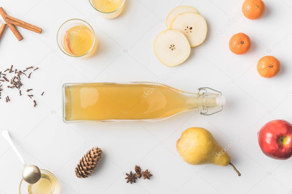 top view of bottle of cider with ingredients around on white tabletop