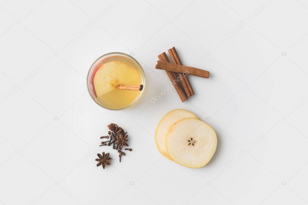 top view of apple cider composition with spices and pear slices on white tabletop