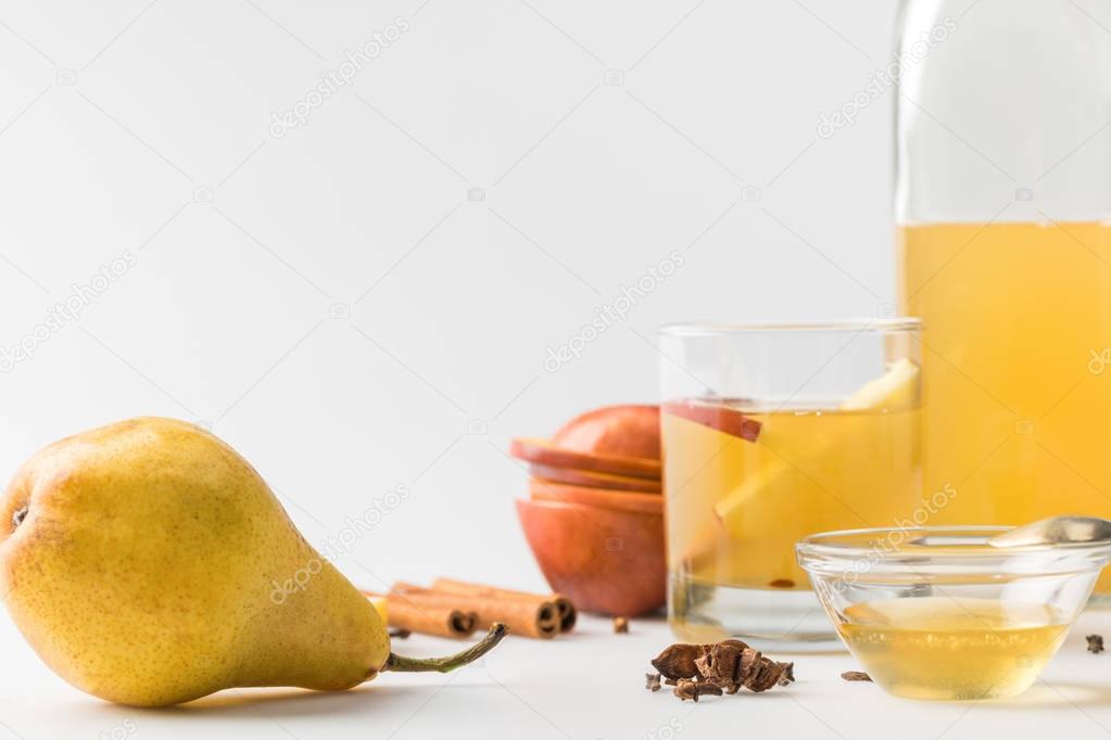 glass of refreshing cider with apple and pear on white table