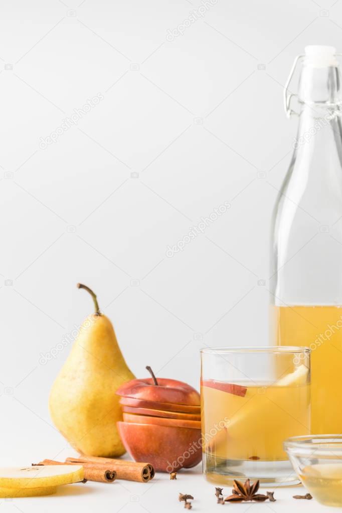 cider in bottle with glass and fruits on white surface