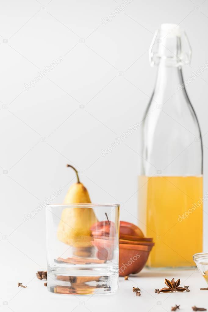 delicious cider in bottle with glass and fruits on white surface