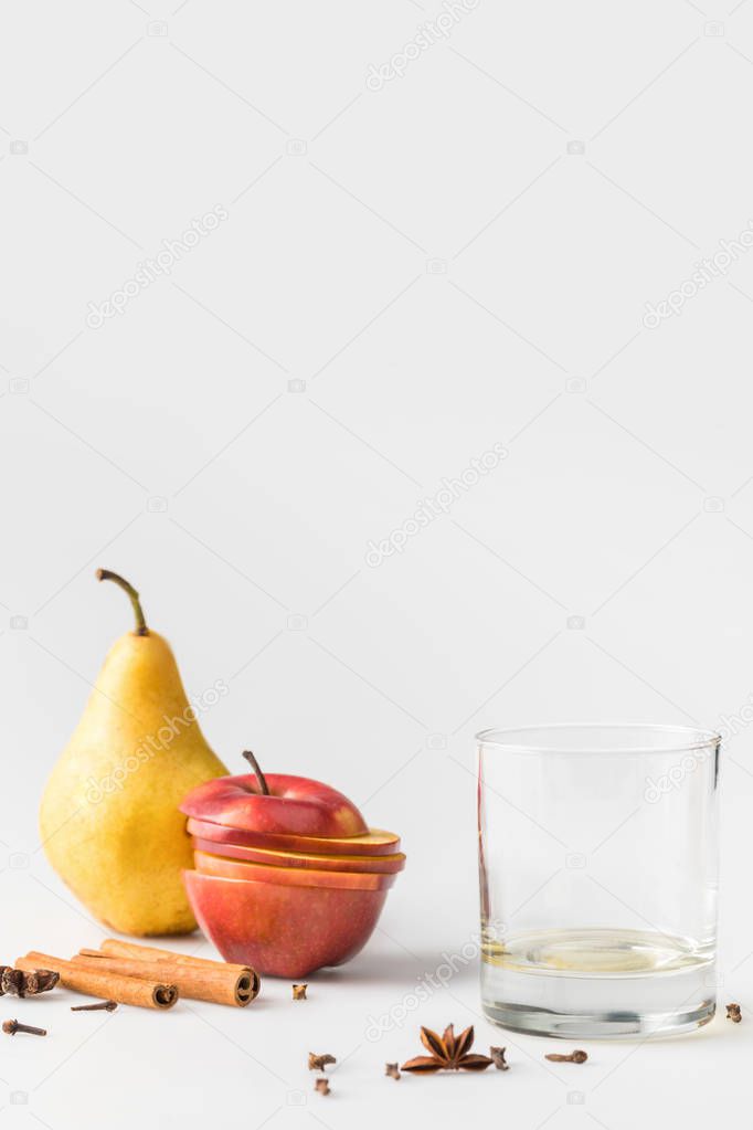empty glass with apple and pear on white surface