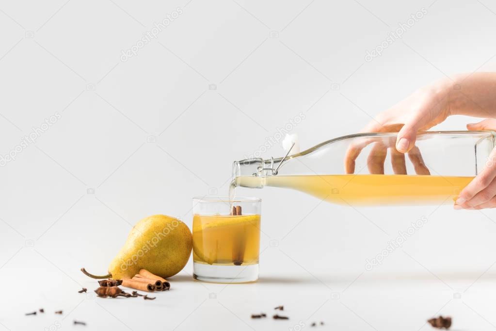 cropped shot of woman pouring delicious pear cider in glass