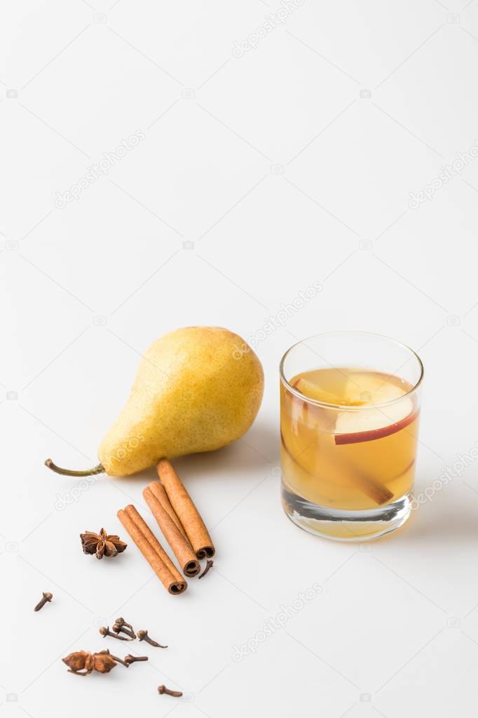 glass of delicious pear cider with spices on white
