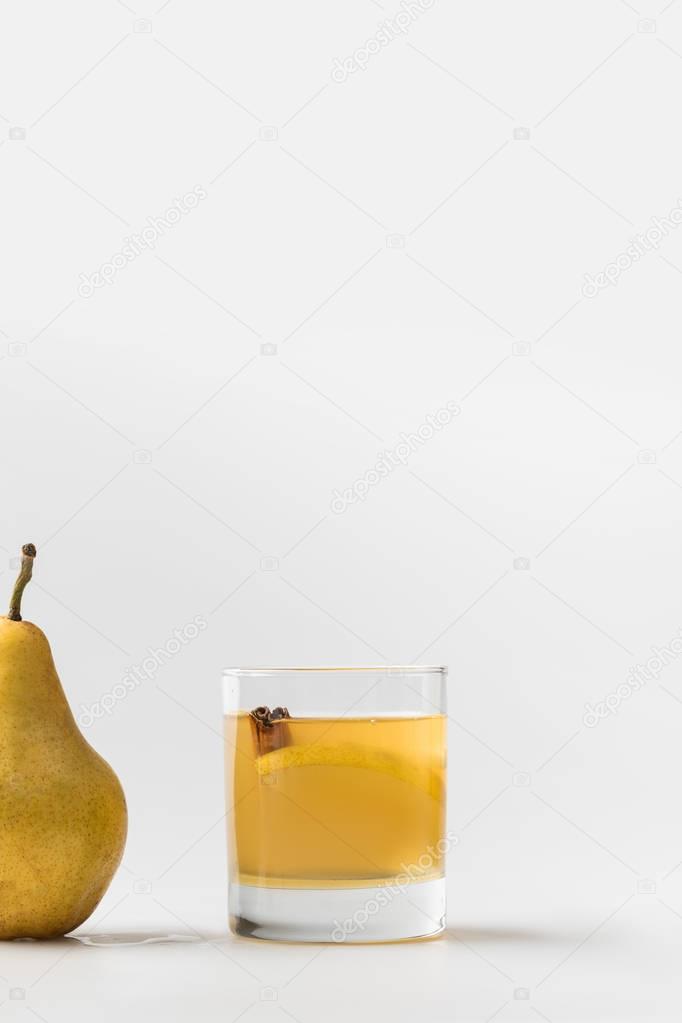 glass of refreshing pear cider with cinnamon on white