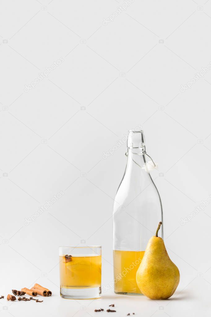 bottle of pear cider with cinnamon and anise on white