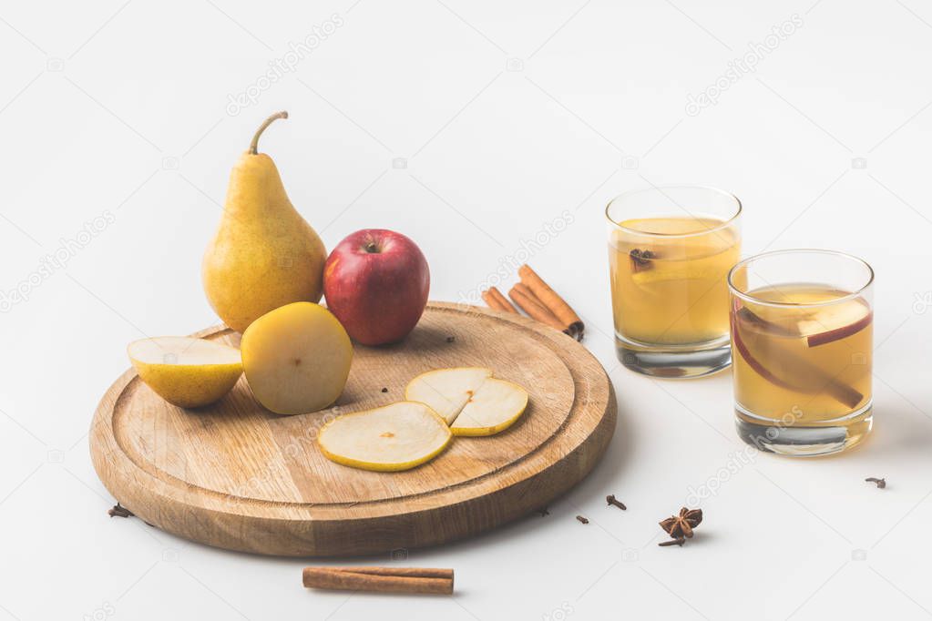 glasses of cider with apple and pear on wooden board on white