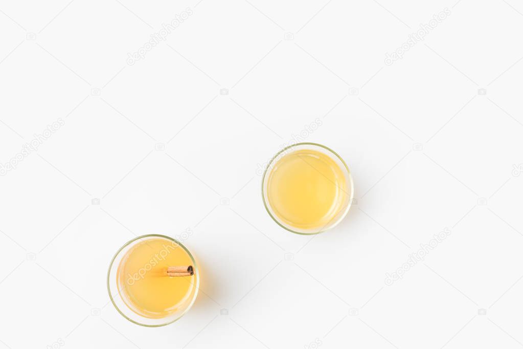 top view of glasses of apple cider with cinnamon stick isolated on white