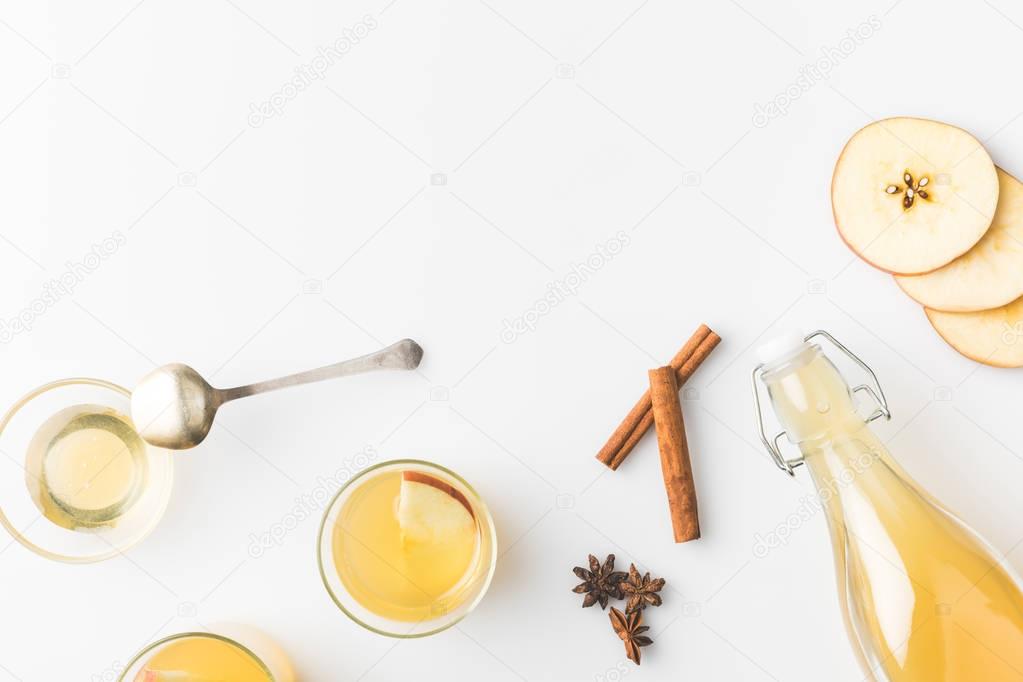 top view of apple cider composition with cinnamon sticks and glasses isolated on white