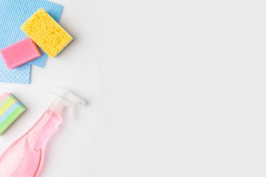 top view of colorful washing sponges and spray bottle, isolated on white clipart