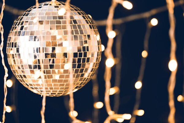 glossy disco ball with garland on black background