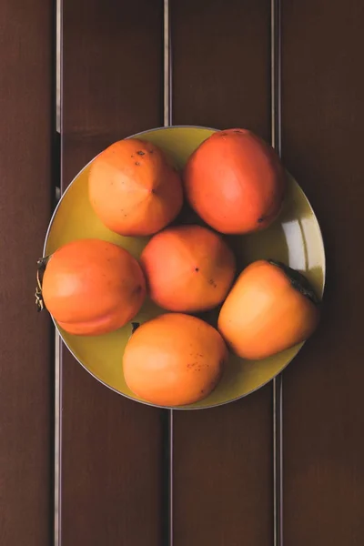 Sett Ovenfra Gul Plate Med Oransje Persimmons – stockfoto
