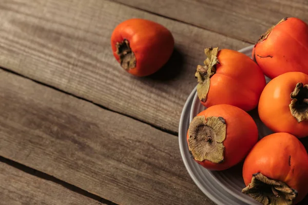 灰色の木製テーブルに熟したオレンジ柿 — ストック写真
