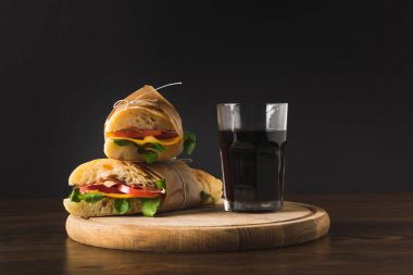 two panini on each other and glass of cola on wooden board  clipart