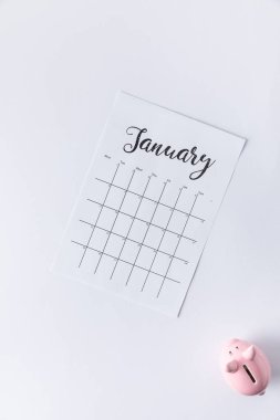 top view of part of calendar with january lettering and piggy bank isolated on white clipart