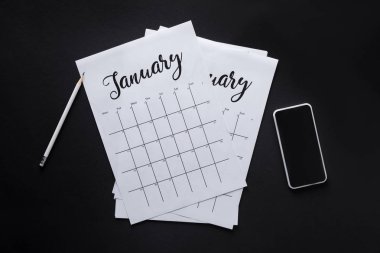 flat lay with paper calendar, smartphone and pencil isolated on black clipart
