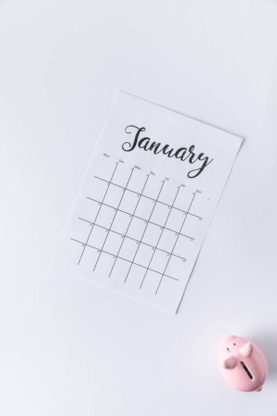 top view of part of calendar with january lettering and piggy bank isolated on white