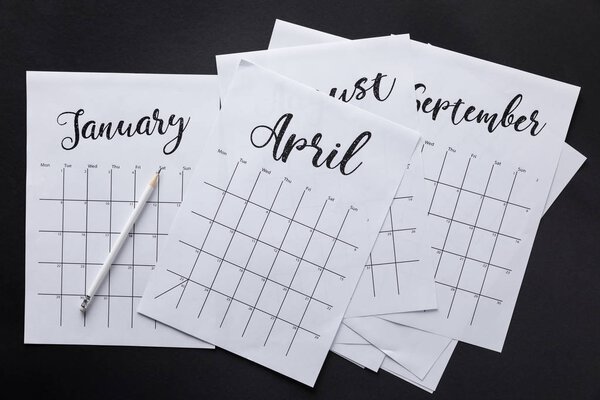 плоский лежал с бумажным календарем и карандашом изолированы на черном
