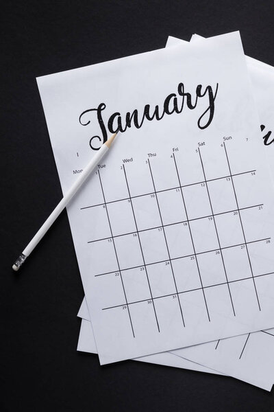 плоская кровать с устроенными календарными бумагами и карандашом, изолированными на черном
