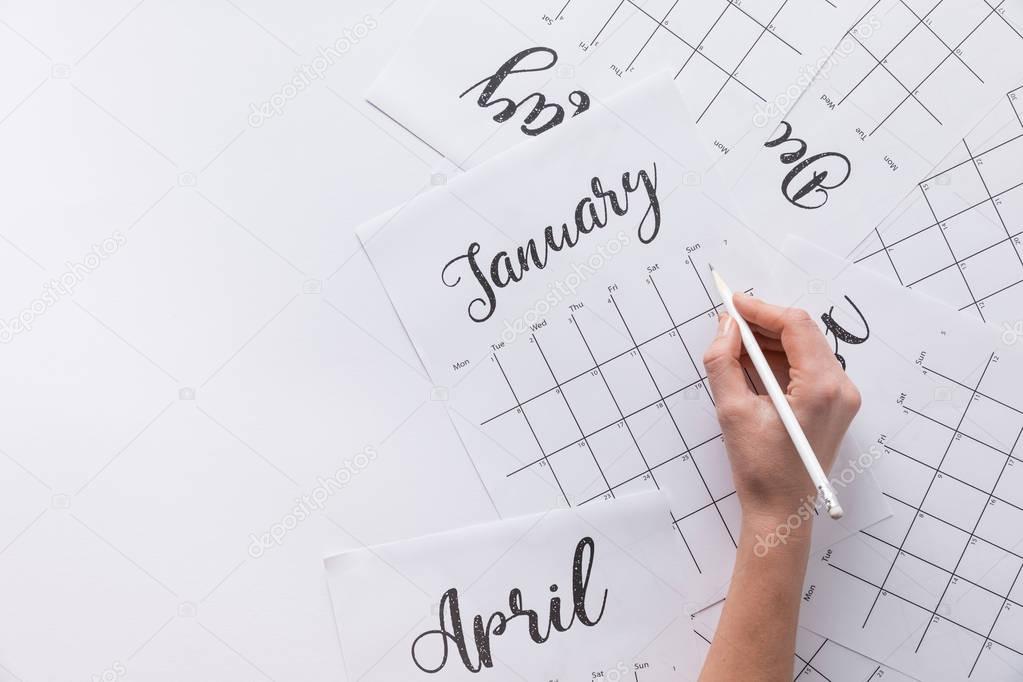 partial view of woman making notes in calendar isolated on white
